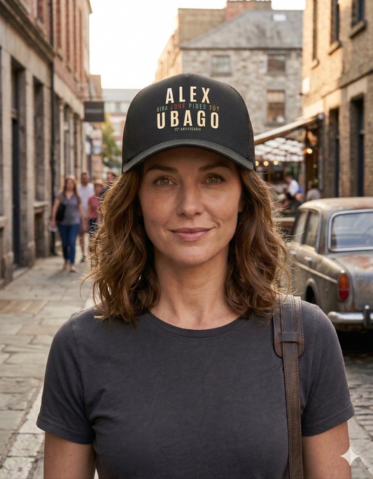 Mujer usando la gorra oficial de Alex Ubago 25 Aniversario en una calle cálida, toma media mostrando el diseño frontal.