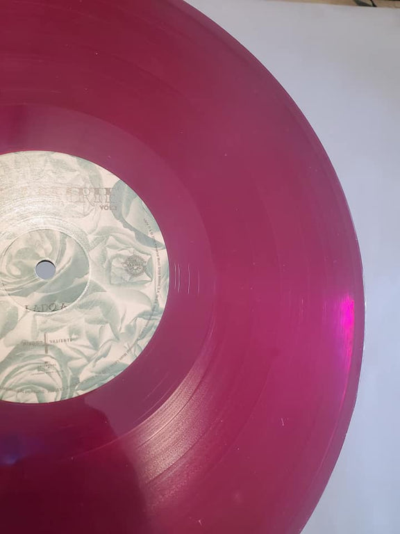 Plano de detalle en primer plano del disco de vinilo translúcido color magenta de Mon Laferte, destacando su etiqueta central impresa con sutiles patrones claros.