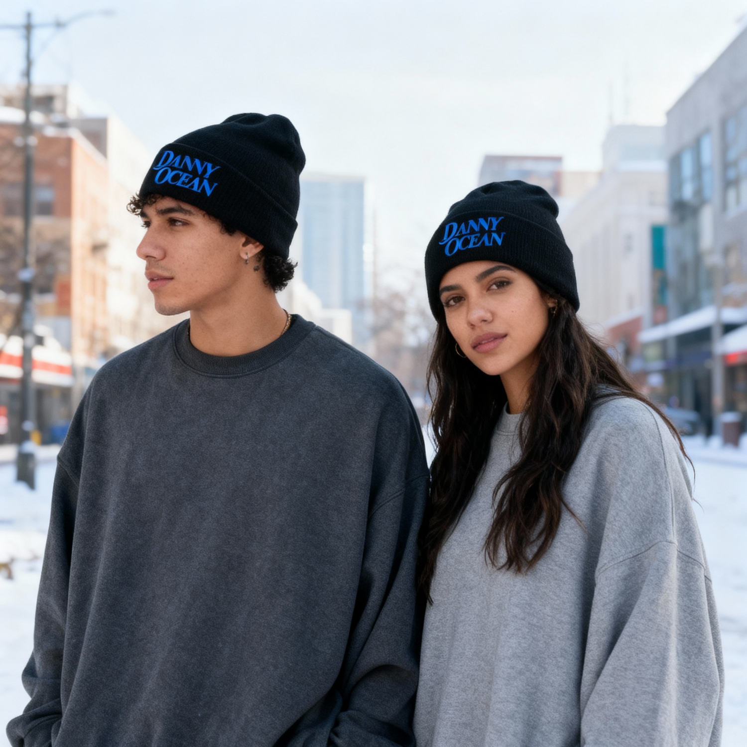 Pareja usando el gorro tipo beanie oficial de Danny Ocean en color negro con bordado azul, ideal para la temporada de invierno y estilo urbano.