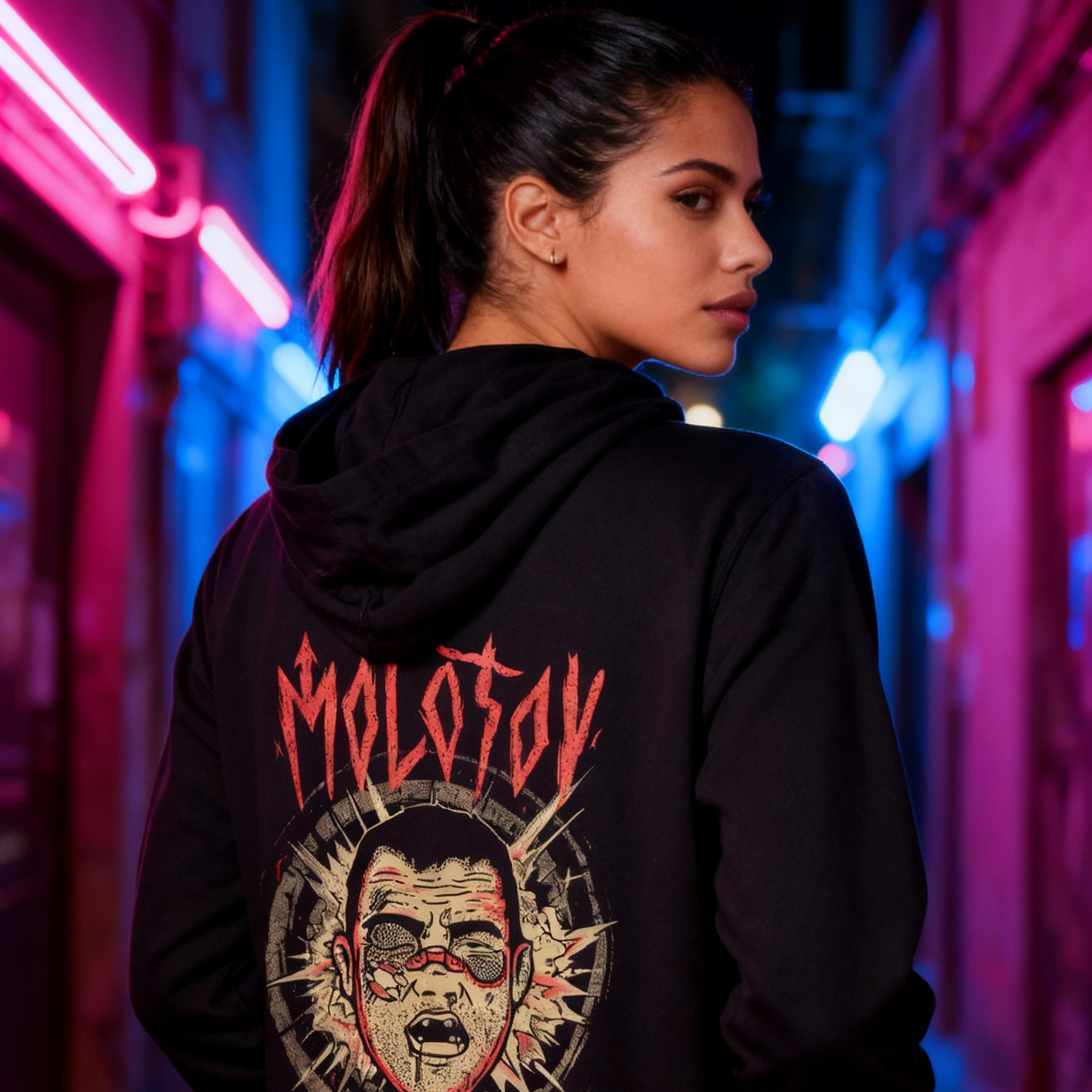 Person wearing a black hoodie with a graphic design in a neon-lit alleyway