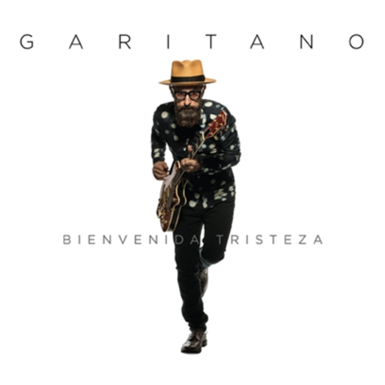 Arte de portada oficial del álbum Bienvenida Tristeza de Garitano, con el artista cargando una guitarra sobre un fondo blanco limpio.