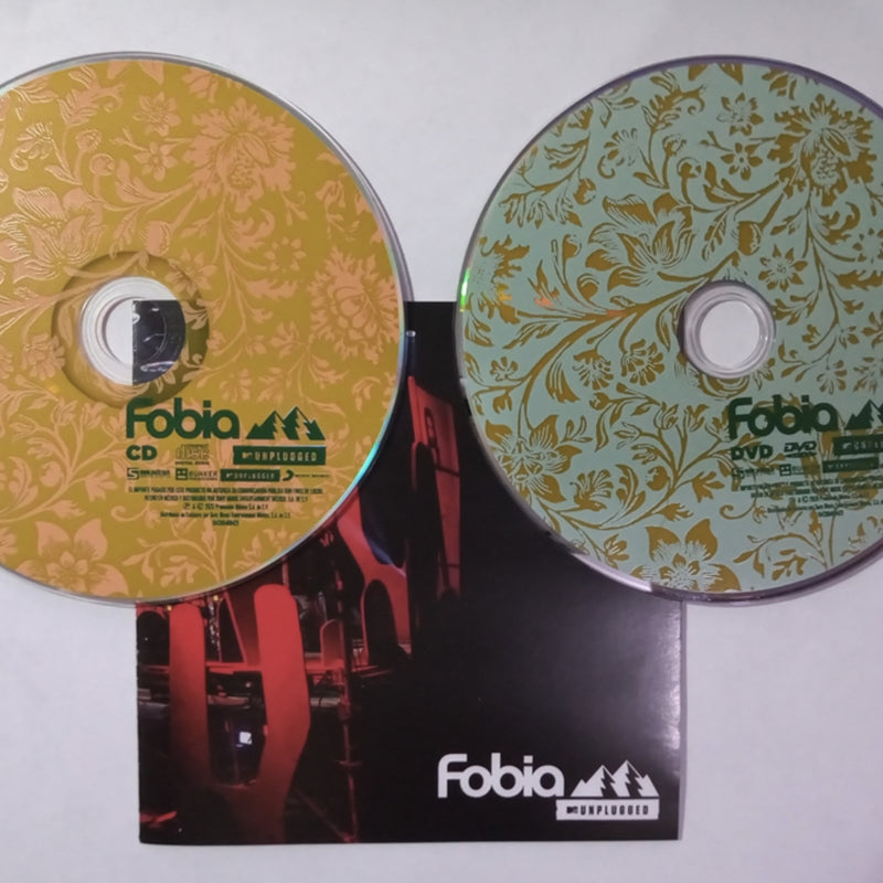 Fotografía del interior del empaque digipak que muestra el set de discos CD y DVD importados de Fobia MTV Unplugged con diseños impresos en tonos dorados.