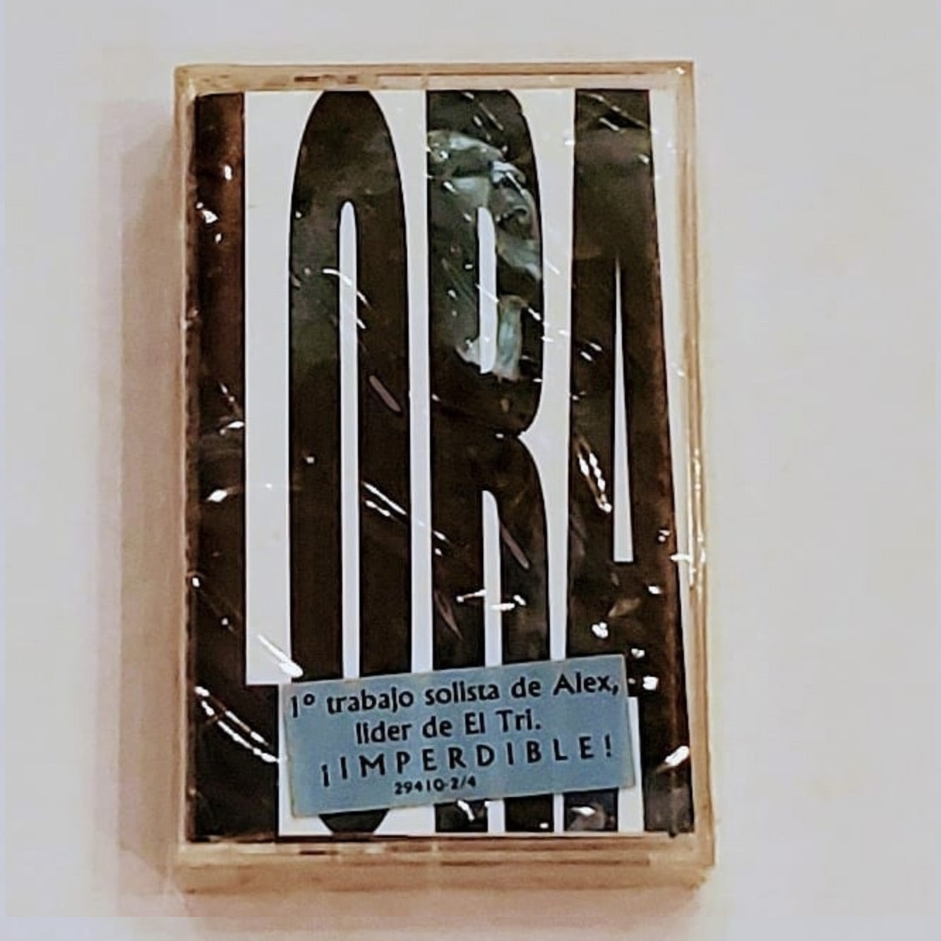 Fotografía en primer plano del cassette original de Alex Lora titulado Lora, Su Lira Y Sus Rolas, mostrando el arte de portada de época y los detalles del cartucho.