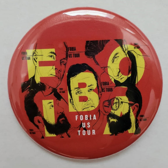 Fotografía en primer plano del pin metálico oficial de la banda Fobia, mostrando el diseño del logotipo con acabados detallados en esmalte.