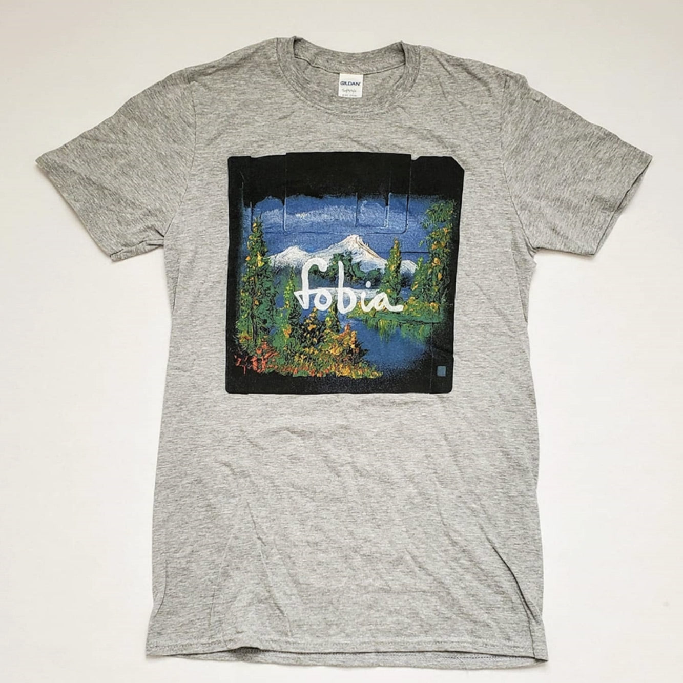 Fotografía de la vista frontal de la playera gris oficial de Fobia, mostrando el diseño de cuello redondo y el logotipo de la banda estampado en el pecho.