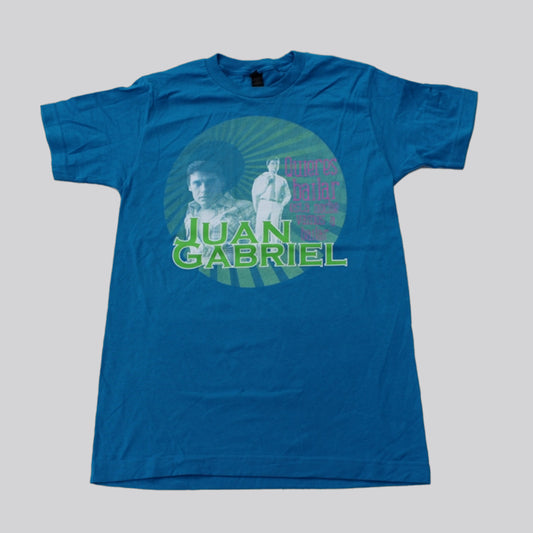 Fotografía de catálogo de la playera azul oficial de Juan Gabriel, mostrando el corte textil y el diseño gráfico circular centrado en el pecho.