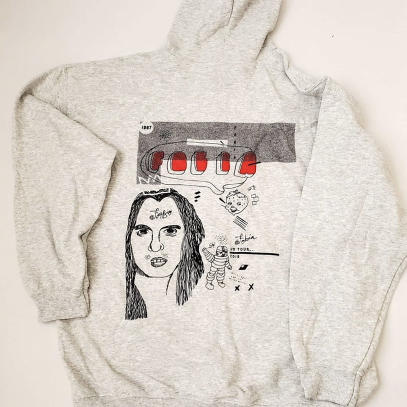 Fotografía de la parte trasera de la sudadera gris de Fobia, destacando el gran gráfico estampado en la espalda con un retrato artístico y detalles en rojo.