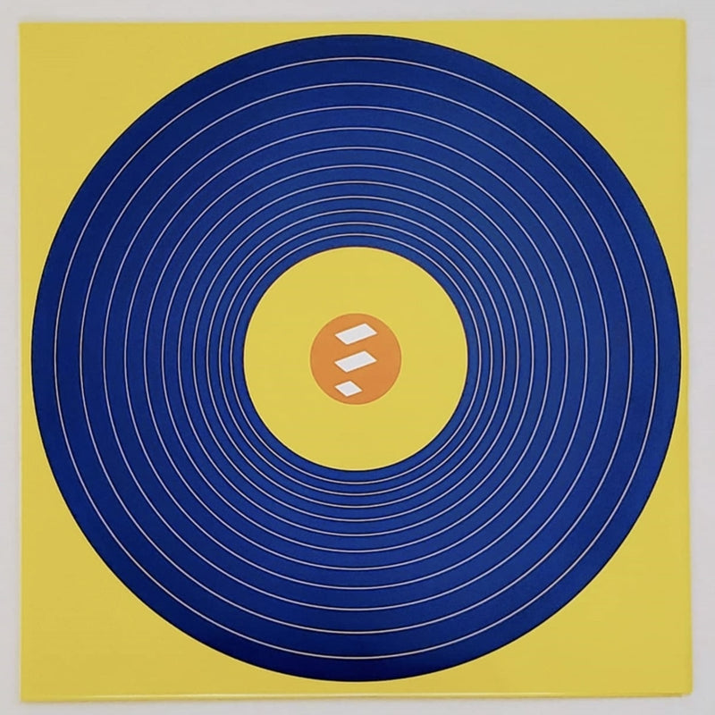 Fotografía del diseño interior de círculos concéntricos azules sobre un fondo amarillo brillante que acompaña los insertos de la edición física.