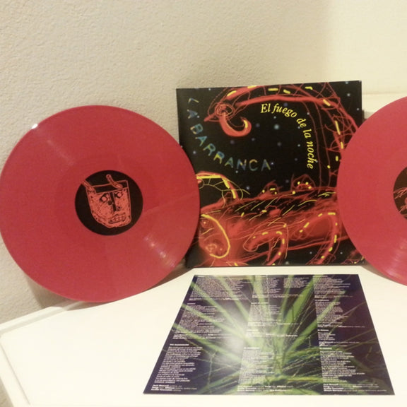 Fotografía que muestra los dos discos de vinilo de color rojo de 180 gramos del álbum El Fuego De La Noche de La Barranca junto a su funda interior impresa con el diseño artístico.