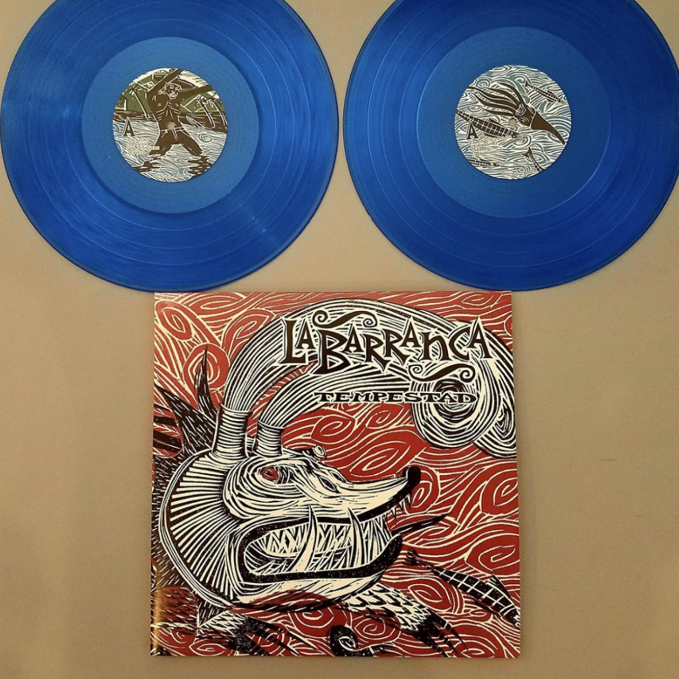 Fotografía de la portada oficial del álbum Tempestad de La Barranca acompañada por sus dos discos de vinilo traslúcidos de color azul de la edición limitada.